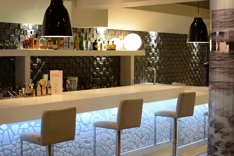 Le comptoir éclairé du bar et ses tabourets