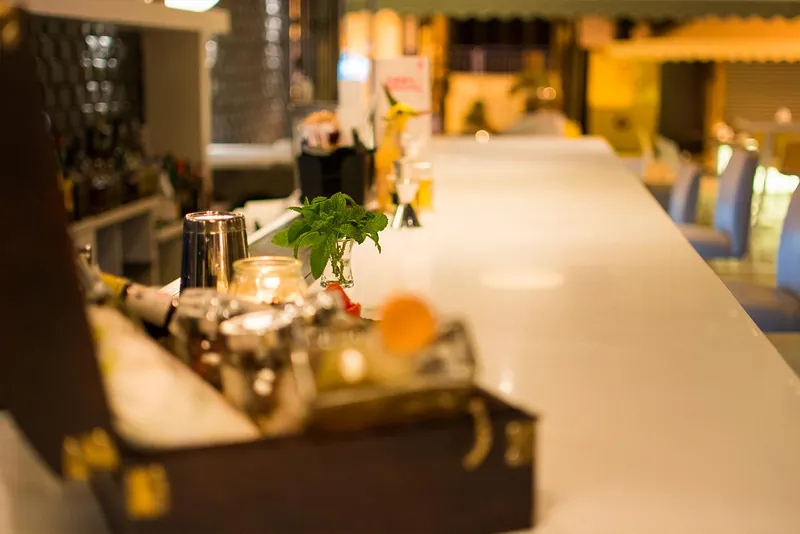 Des ustensiles à cocktail et une plante au bout du comptoir