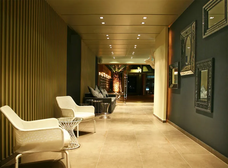 Un couloir du lobby avec des fauteuils blancs et des miroirs encadrés