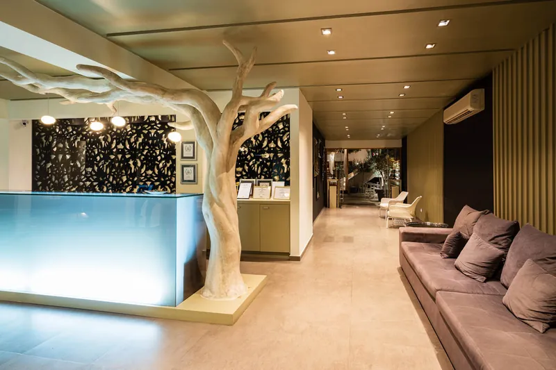 La réception éclairée, l’arbre sculpté et le canapé du lobby