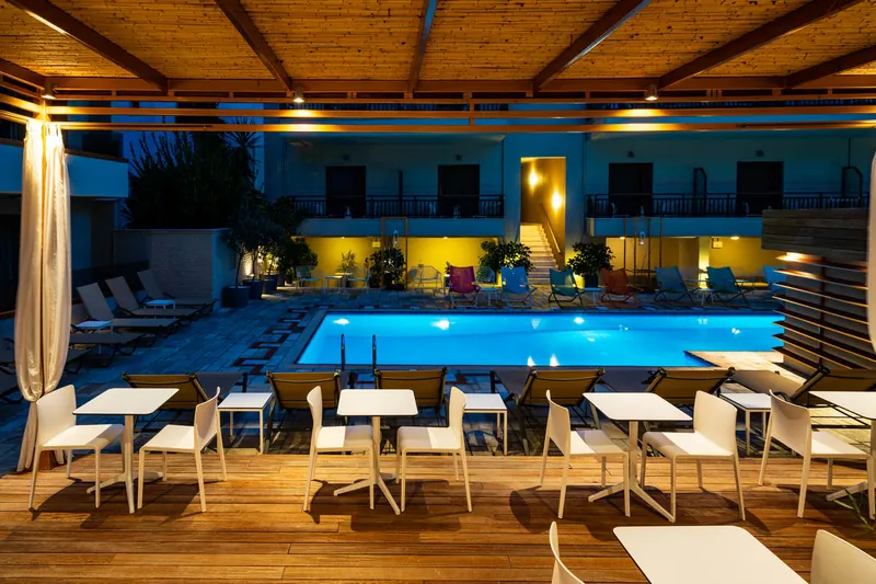 La piscine extérieure au crépuscule, l’hôtel éclairé derrière