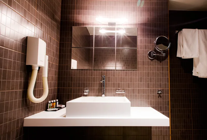 Le lavabo de la salle de bains carrelée de sombre d’une chambre Premium