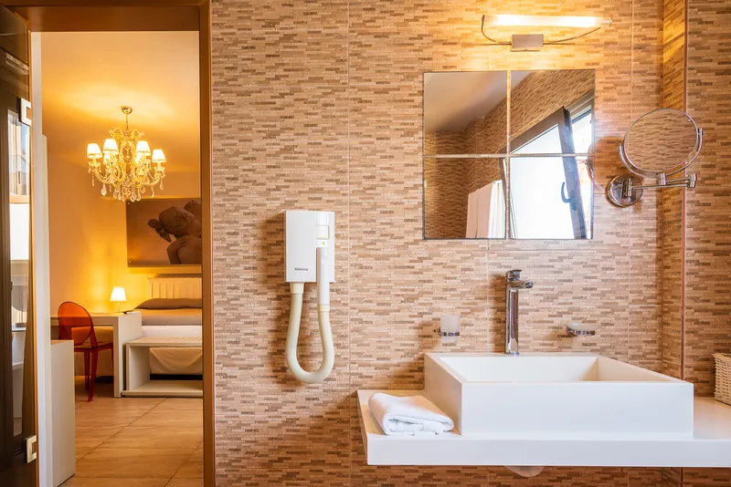 Le lavabo d’une chambre Premium, avec la chambre et son lustre au-delà