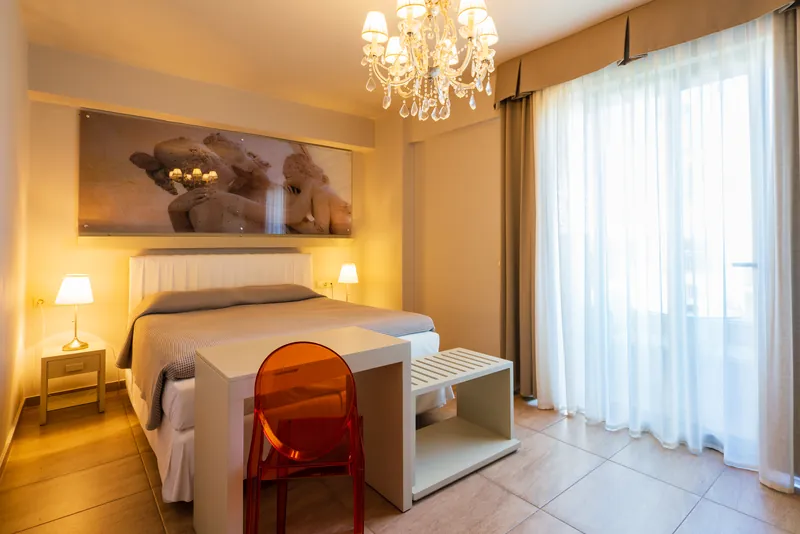 Une chambre Premium avec un lustre et une chaise orange au bureau