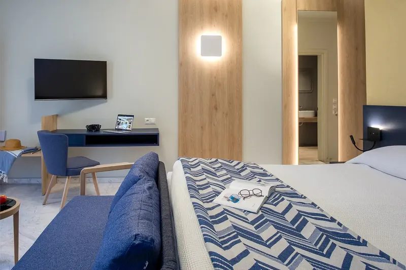 Le canapé bleu au pied du lit d’une chambre supérieure