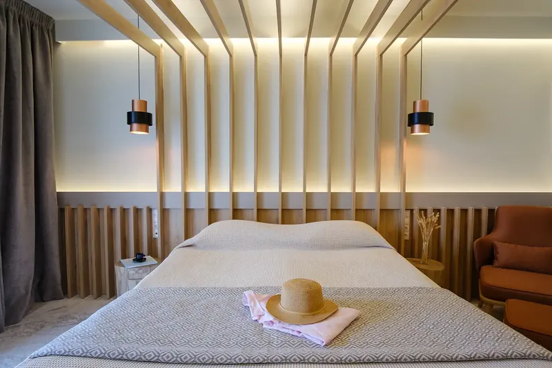 Le lit d’une chambre supérieure sous les lattes de bois, avec un chapeau de paille